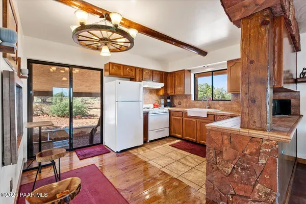 a kitchen with a refrigerator a sink dishwasher a stove and a dining table with wooden floor