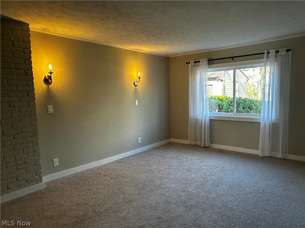 2447 Dysart Road Cleveland, OH 44118 - Photo 10 of 20 Carpeted spare room featuring a textured ceiling, crown molding, and brick wall