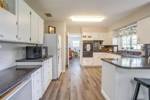 a large kitchen with stainless steel appliances granite countertop a lot of counter space and wooden floors