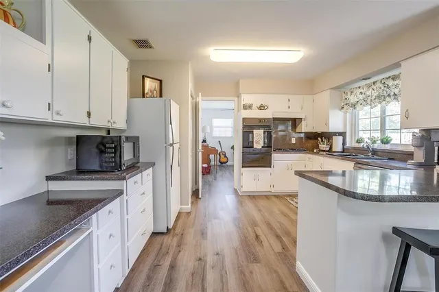 a large kitchen with stainless steel appliances granite countertop a lot of counter space and wooden floors