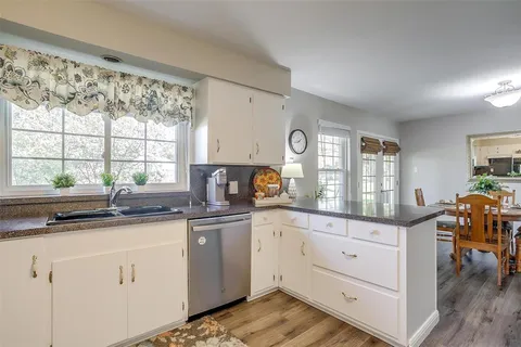 a kitchen with white cabinets and wooden floor