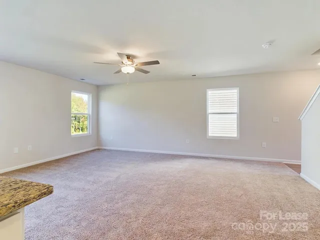 an empty room with windows and ceiling fan