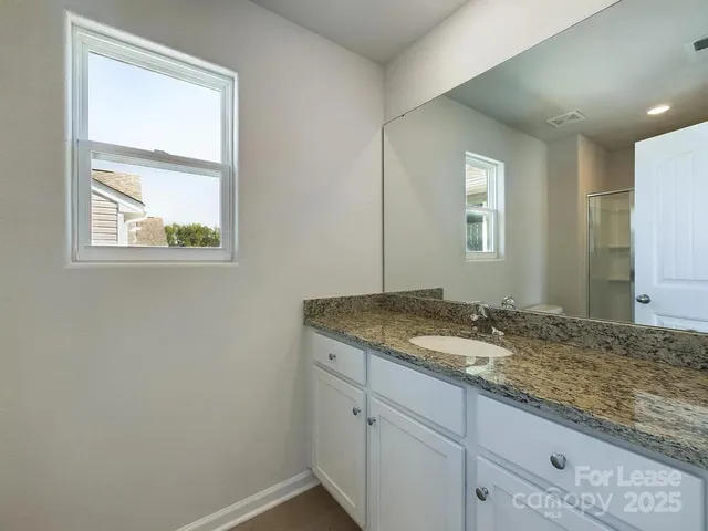 a bathroom with a granite countertop sink and mirror next to a window