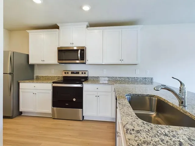 a kitchen with granite countertop a sink a stove and refrigerator
