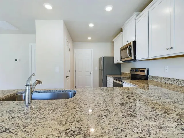 a kitchen with granite countertop a stove a sink and a microwave