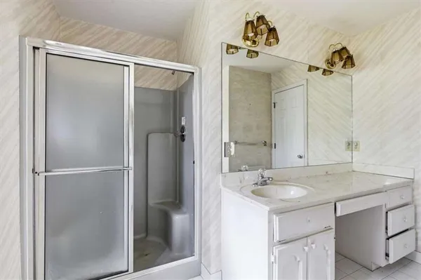 a bathroom with a sink vanity and shower