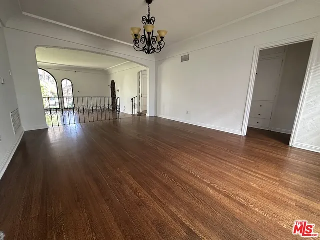 a hallway with wooden floor chandelier and entryway