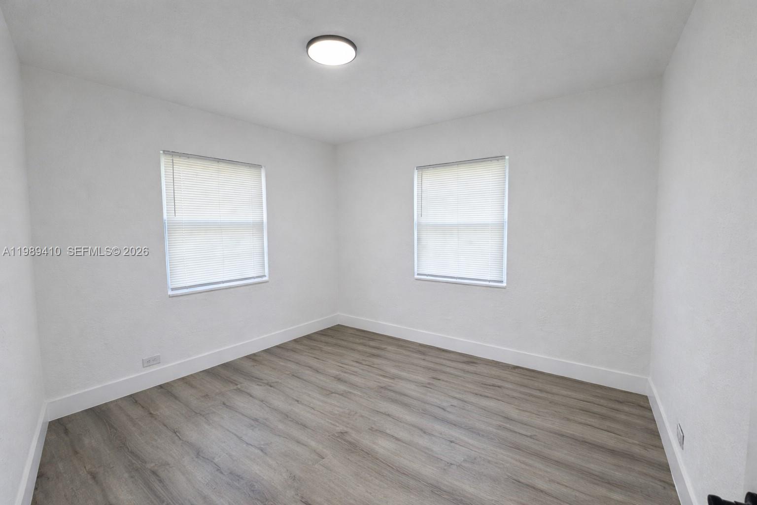 2450 Northwest 157th St Road Miami Gardens, FL 33054 - Photo 13 of 24 an empty room with wooden floor and windows