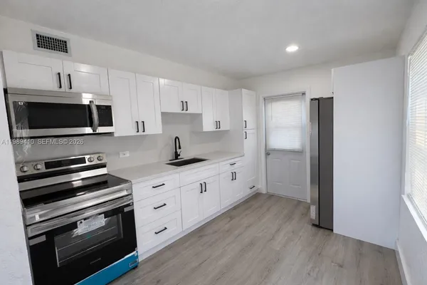 a kitchen with stainless steel appliances a stove a sink and a microwave