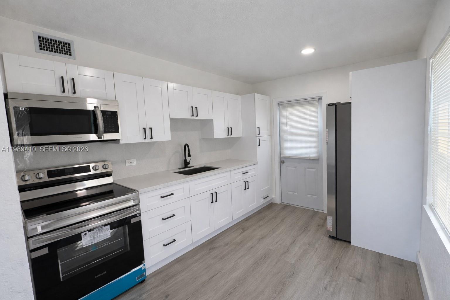2450 Northwest 157th St Road Miami Gardens, FL 33054 - Photo 6 of 24 a kitchen with stainless steel appliances a stove a sink and a microwave