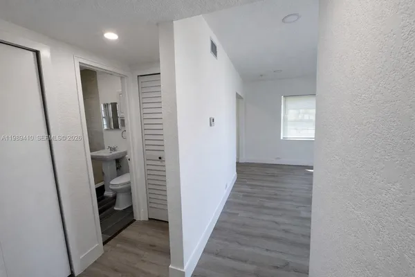a view of a hallway with wooden floor and closet