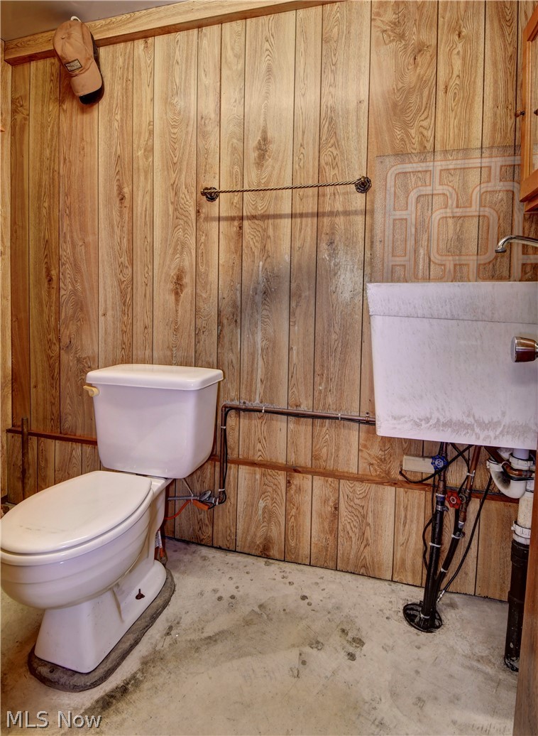 3464 Ridge Road Northwest Strasburg, OH 44680 - Photo 39 of 49 Bathroom featuring sink, toilet, concrete flooring, and wooden walls