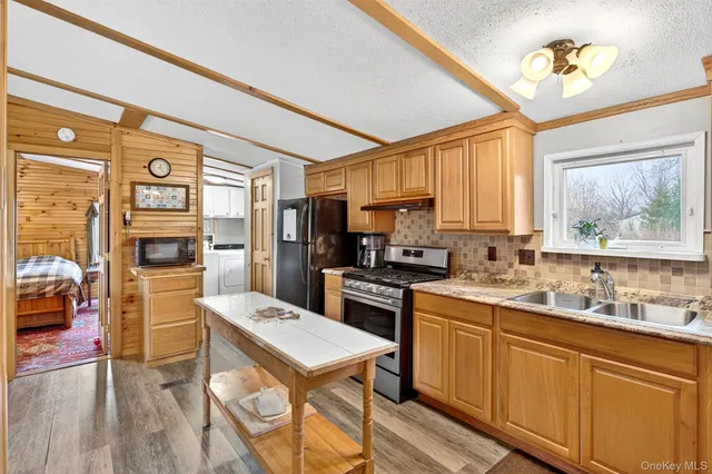 a kitchen with a refrigerator a stove a sink dishwasher a dining table and chairs with wooden floor