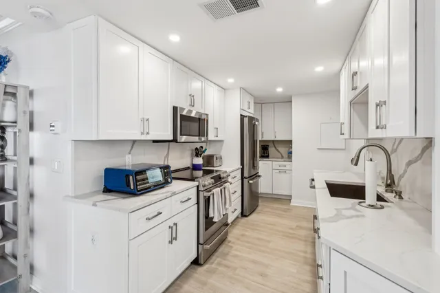 a kitchen with white cabinets and stainless steel appliances
