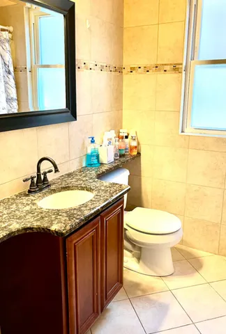 a bathroom with a granite countertop sink and a toilet