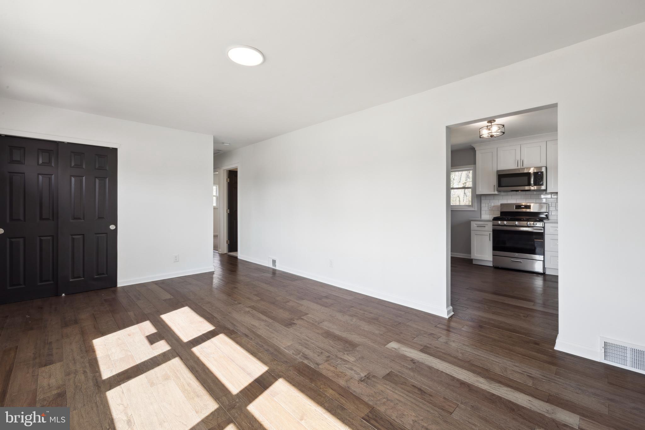 324 Baldwin Road Glassboro, NJ 08028 - Photo 3 of 14 an empty room with wooden floor kitchen view and windows
