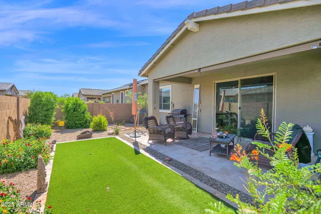 a view of a patio with table and chairs potted plants and floor to ceiling window