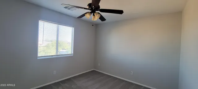 an empty room with a window and a fan