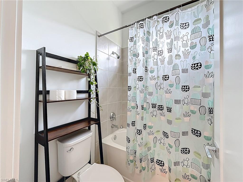 5277 Lamone Ln Avenue Immokalee, FL 34142 - Photo 12 of 27 a bathroom with a shower curtain and a toilet
