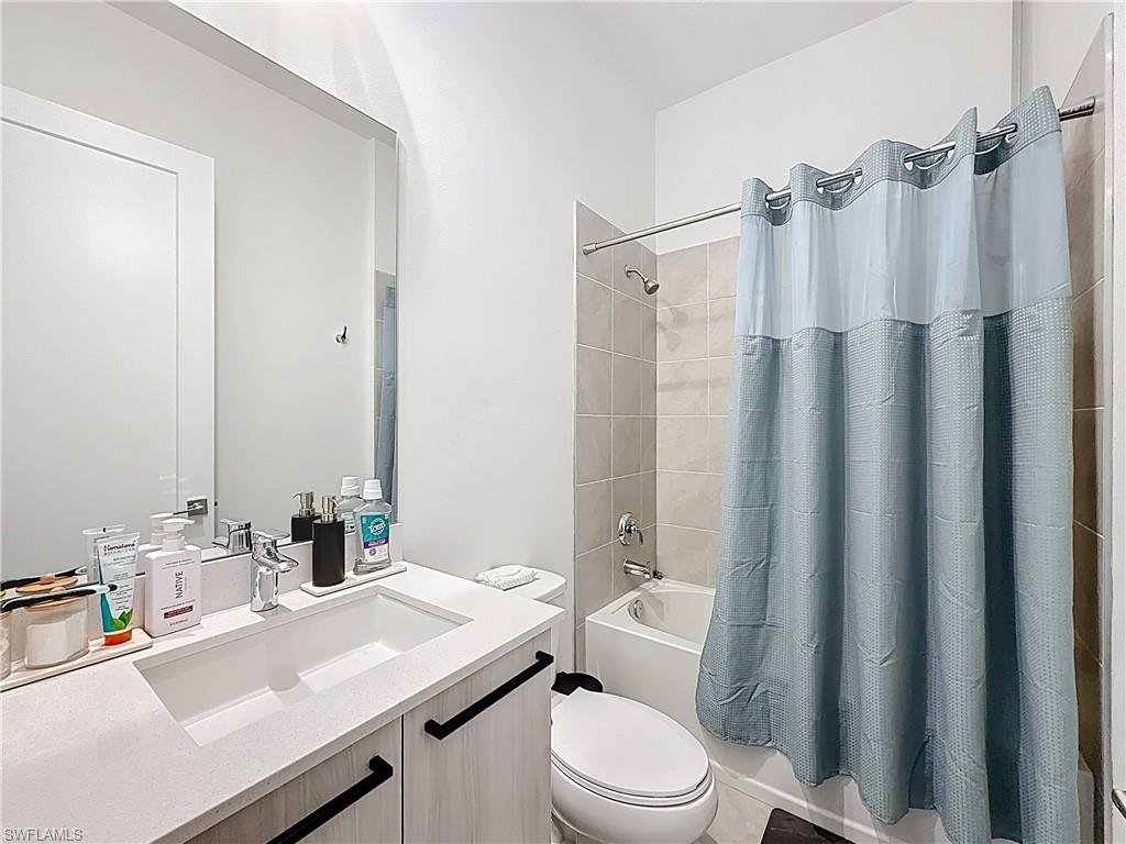 5277 Lamone Ln Avenue Immokalee, FL 34142 - Photo 16 of 27 a bathroom with a sink a toilet a mirror and shower curtain