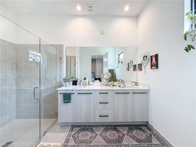 a bathroom with a double vanity sink toilet mirror and shower