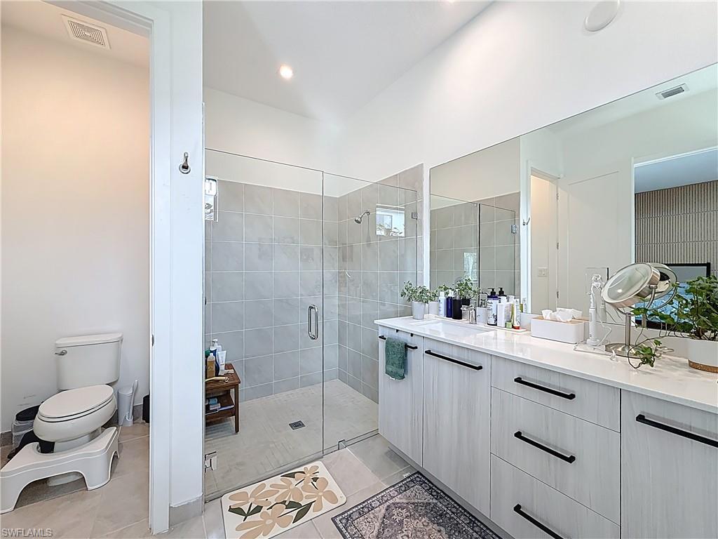 5277 Lamone Ln Avenue Immokalee, FL 34142 - Photo 19 of 27 a bathroom with a double vanity sink toilet mirror and shower