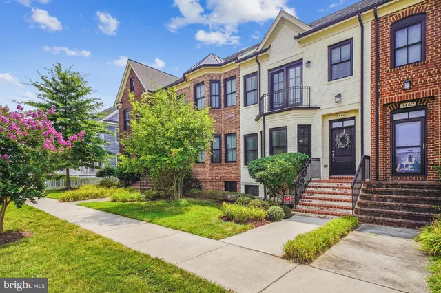 a front view of a multi story residential apartment building with yard and green space