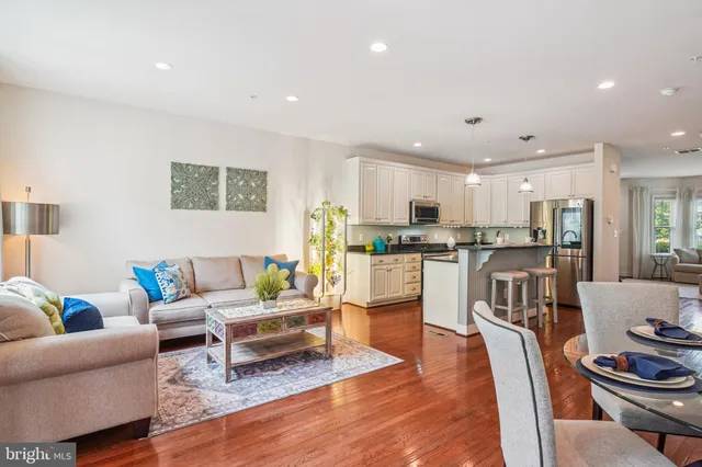 a living room with stainless steel appliances kitchen island granite countertop furniture and a dining table with wooden floor