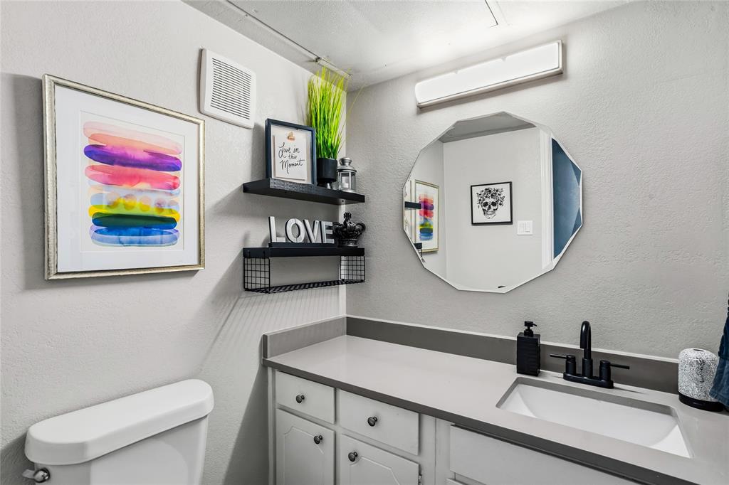 5540 Boca Raton Boulevard, Unit 181 Fort Worth, TX 76112 - Photo 11 of 21 Downstairs guest bath with a vanity area featuring a light gray countertop with an integrated rectangular sink, matte black faucet, and white cabinetry
