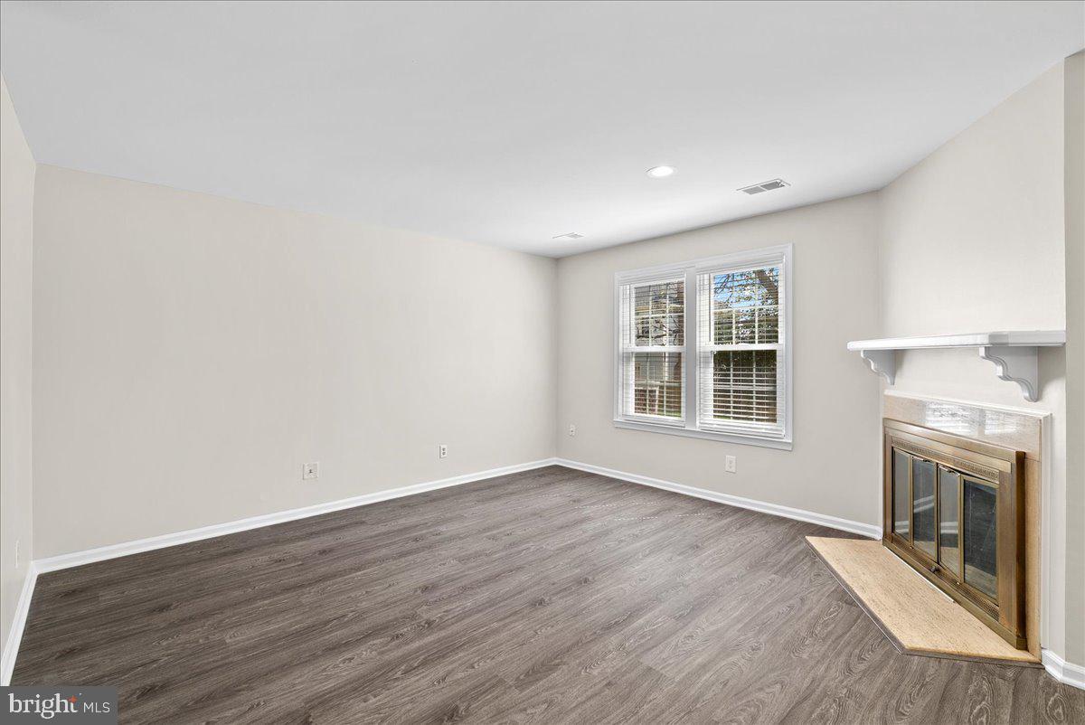 12942 A Grays Pointe Road, Unit 12942A Fairfax, VA 22033 - Photo 4 of 22 an empty room with wooden floor fireplace and windows