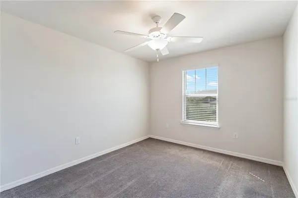 a view of an empty room with a chandelier fan