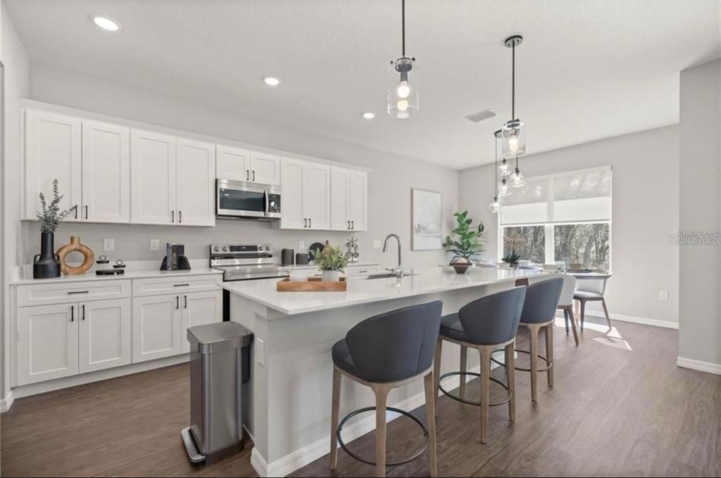 5550 Southwest 107th Street Ocala, FL 34476 - Photo 3 of 15 a kitchen with stainless steel appliances a dining table chairs sink and cabinets