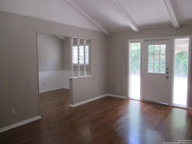 an empty room with wooden floor and windows