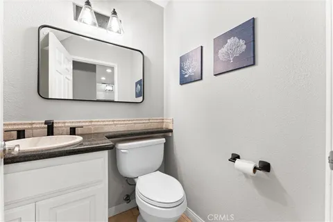 a bathroom with a toilet sink vanity and mirror