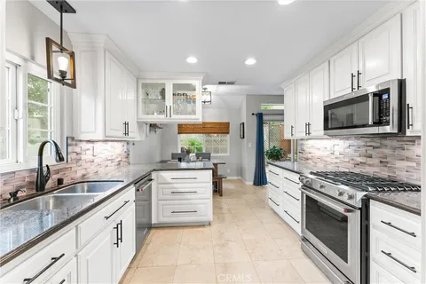 a kitchen with stainless steel appliances granite countertop a stove top oven a sink dishwasher a refrigerator and a oven with wooden floor