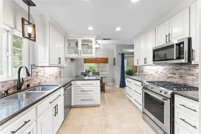 a kitchen with stainless steel appliances granite countertop a stove top oven a sink dishwasher a refrigerator and a oven with wooden floor