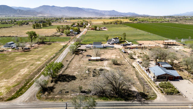 1211 West Midvalley Road Cedar City, UT 84721 - Photo 1 of 14 Expansive rural property featuring an established structure with a metal roof and red siding, multiple outbuildings, and extensive undeveloped land