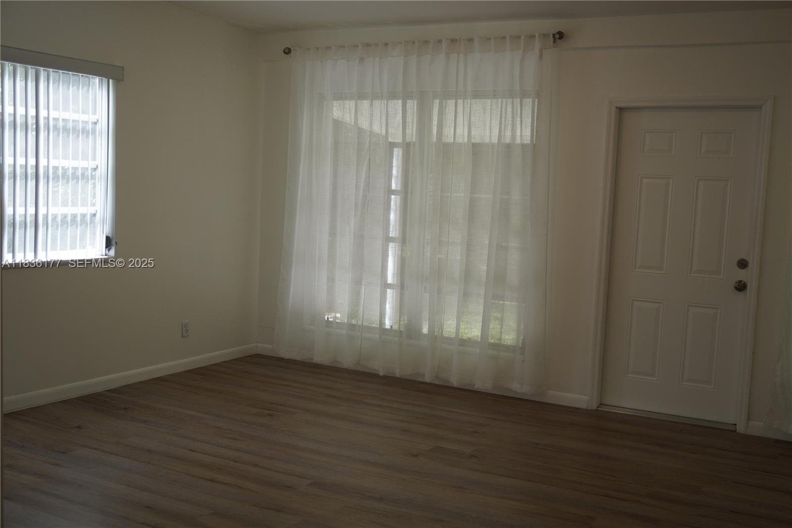 7800 Southwest 69th Avenue Miami, FL 33143 - Photo 11 of 24 an empty room with wooden floor and windows with curtains