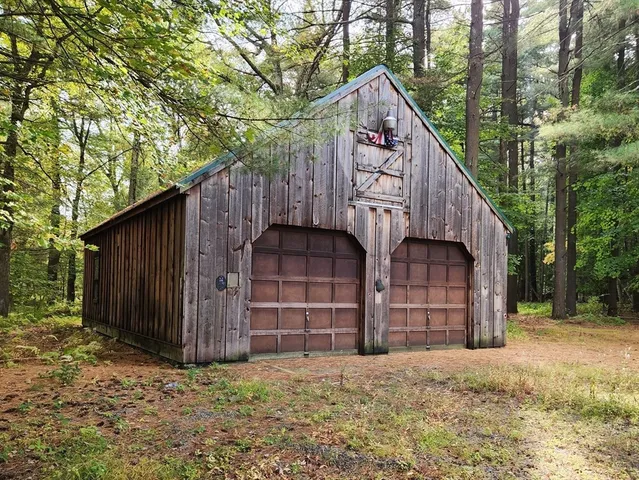 a view of a wooden house with large trees and wooden fence