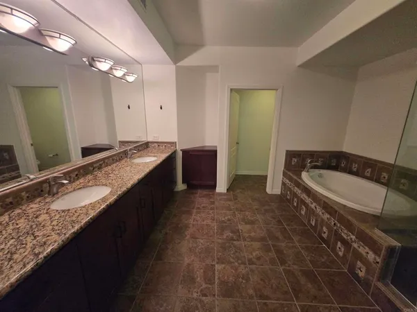a spacious bathroom with a granite countertop bathtub sink and mirror