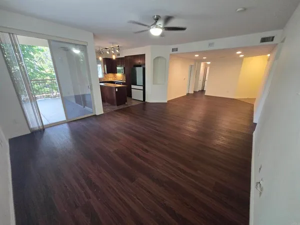 a view of a big room with wooden floor and a kitchen