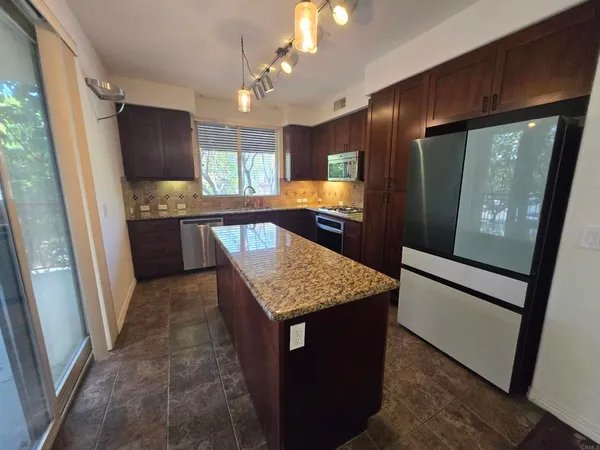 a kitchen with kitchen island granite countertop lots of counter top space and stainless steel appliances
