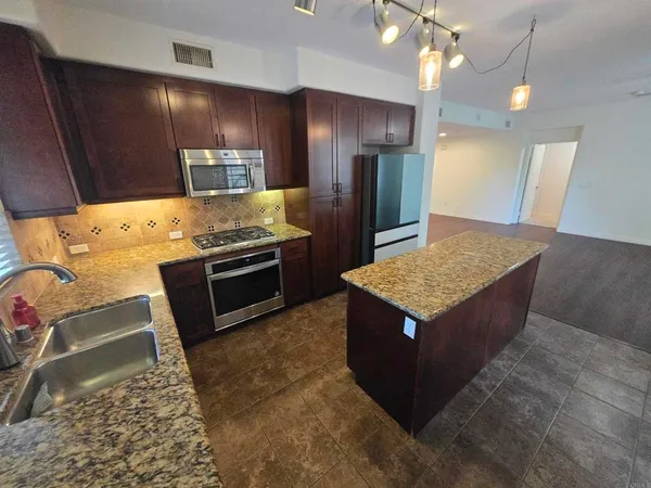 a kitchen with stainless steel appliances granite countertop a sink stove and refrigerator
