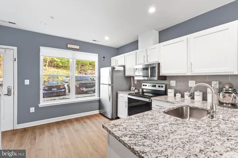 a kitchen with stainless steel appliances a refrigerator a stove top oven a sink a refrigerator and white cabinets