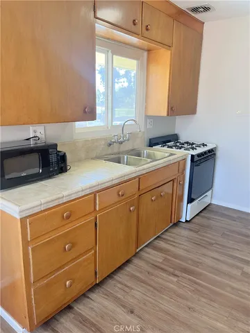 a kitchen with stainless steel appliances granite countertop a sink a stove and a wooden floors