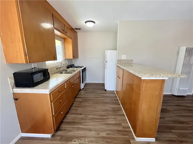 a kitchen with sink a refrigerator and wooden cabinets