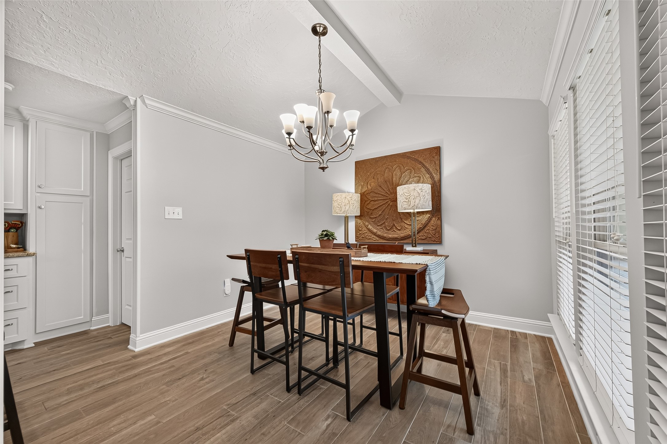 24719 Wilderness Road Spring, TX 77380 - Photo 15 of 42 This dining area features a cozy table set under a stylish chandelier, with wood-like ceramic tile flooring and plenty of natural light from large windows.
