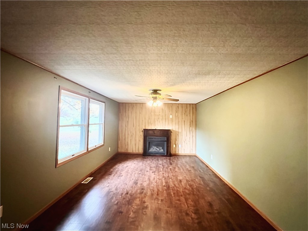 3122 Bedrock Road Northwest Dellroy, OH 44620 - Photo 9 of 23 Unfurnished living room featuring ceiling fan, ornamental molding, dark hardwood / wood-style floors, and a textured ceiling