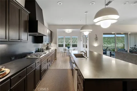 a kitchen with stainless steel appliances a stove a sink a microwave a dining table and chairs