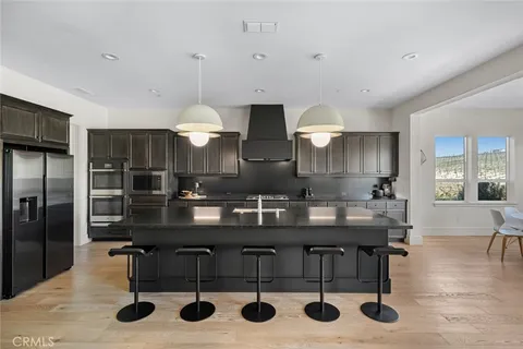 a kitchen with stainless steel appliances a stove a sink a microwave a dining table and chairs